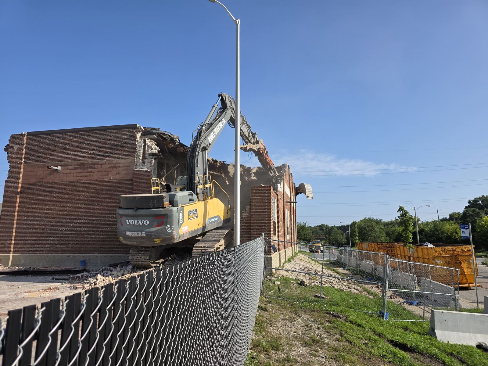 Excavator breaking down the brick walls of a school building