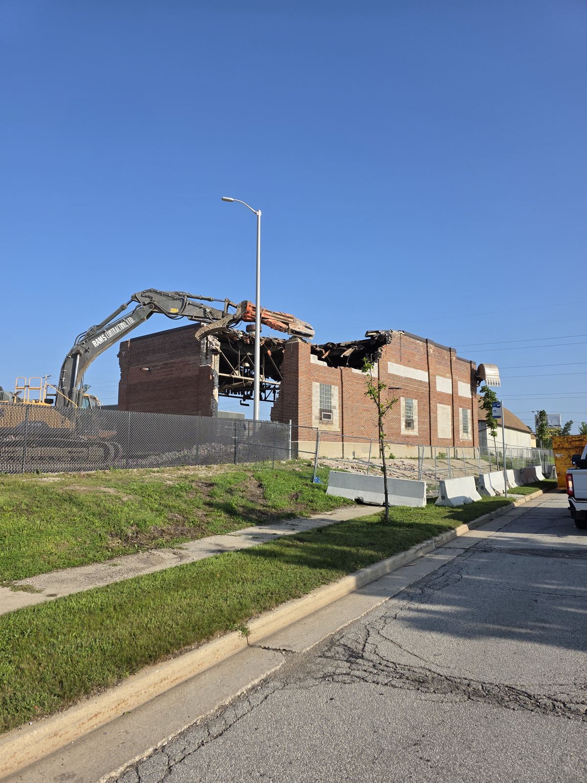 Excavator tearing into a brick school on a demolition site