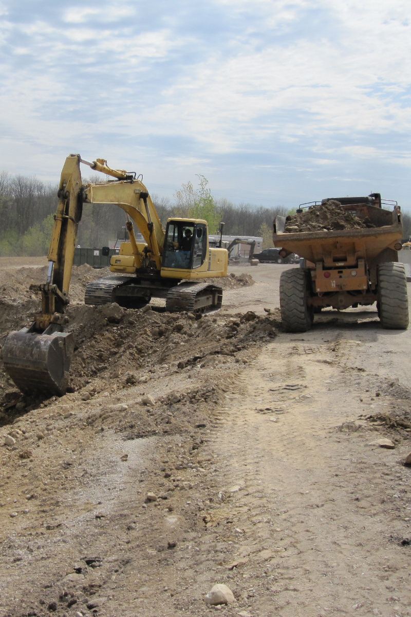Excavator and articulated dump truck working on a graded dirt site